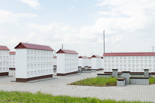 Rows of white walls for the burial of ashes after cremation. Empty cells for urns with ashes. Construction of the columbarium. Benches for resting in the cemetery