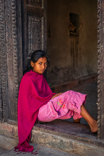 Portrait of young Nepali girl posing in an ancient temple in Bhaktapur. Bhaktapur is an ancient town in the Kathmandu Valley and is listed as a World Heritage Site by UNESCO for its rich culture, temples, and wood, metal and stone artwork.
