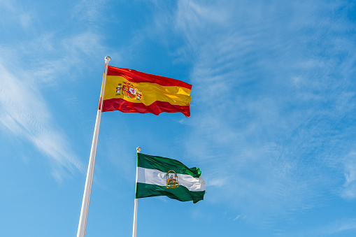 United Kingdom and Spain flag waving in the wind against white cloudy blue sky together. Diplomacy concept, international relations