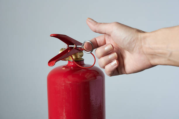 istock Hand holding a red fire extinguisher on grey background, closeup 2134828405
