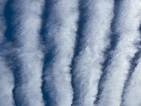Altostratus Undulatus clouds. Wavy stripy cloud formations caused by oscillations in the atmosphere being visualized by condensation or resublimation.