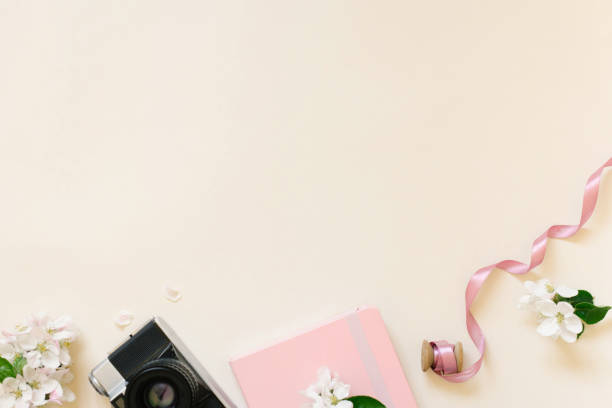 istock Flat lay frame of notepad, camera, spring white apple blossoms on beige background with copy space. Blogger's workplace 2134843184