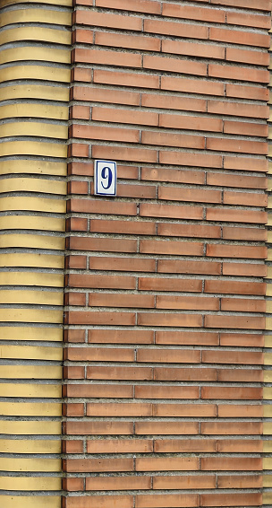 Number plate. Number 9 (nine) against a red brick wall background. Concept from a brick and a wall.