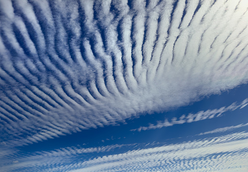 Altostratus Undulatus clouds. Wavy stripy cloud formations caused by oscillations in the atmosphere being visualized by condensation or resublimation.