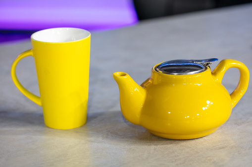 Yellow ceramic teapot and cup on the table in cafe.