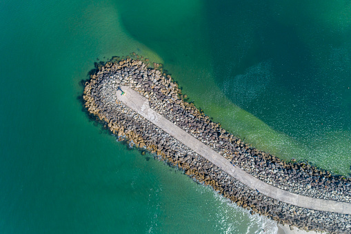 Aerial top view of a groyne on a beach, breakwater for coastal and harbour protection.