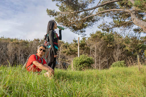 An elderly husband and wife taking a break from hiking in a grass area