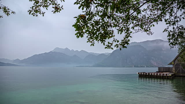 Lake view with mist unfold over majestic mountains, nature timelapse under tree branch