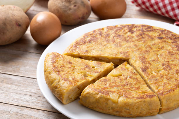 istock Traditional spanish omelette with ingredients on wooden table. 2134891951