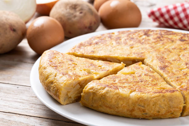 istock Traditional spanish omelette with ingredients on wooden table. 2134892464