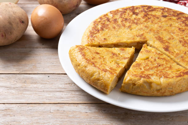 istock Traditional spanish omelette with ingredients on wooden table. 2134892500
