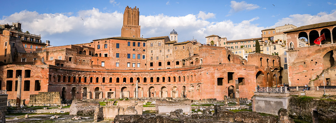 Rome, Italy, March 19 -- An impressive and detailed cityscape of the entire Trajan's Market Forum in the Roman Imperials Forums, in the historic heart of the Eternal City. The Trajan's Markets were built along the side of the Quirinale hill during the reign of the Emperor Trajan (53-117 AD). Considered the oldest commercial center in the world, the arcades and masonry structures of the Trajan's Markets also housed some administrative offices of ancient Rome. In the Middle Ages the markets were converted into military bastions and barracks, with the construction of the Watchtower in 1200 (center). The Roman Forum, one of the largest archaeological areas in the world, represented the political, legal, religious and economic center of the city of Rome, as well as the nerve center of the entire Roman civilization. In 1980 the historic center of Rome was declared a World Heritage Site by Unesco. Image in original 65x24 ratio and high definition quality.