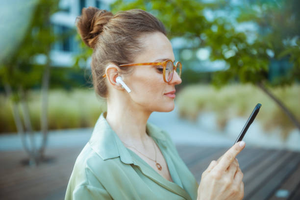 trabajadora relajada de la mujer con blusa verde y anteojos usando el teléfono - easy money audio fotografías e imágenes de stock