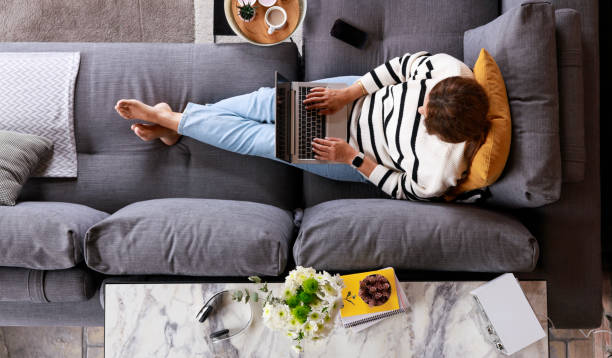 istock Relaxed young woman on sofa with laptop 2134900995