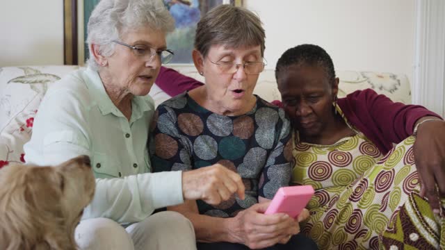 Senior women playing a retro handheld video game together at home