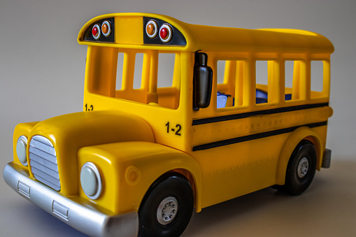 A miniature yellow toy bus against a grey background. Perfect for imaginative play and collectors