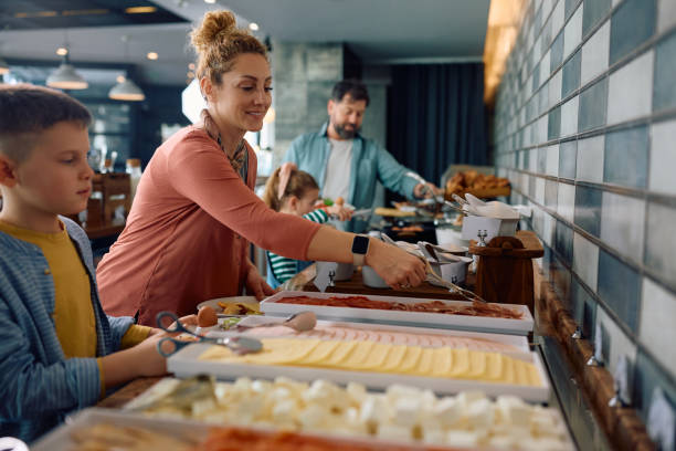 Happy woman having buffet breakfast with her family while staying in a hotel.