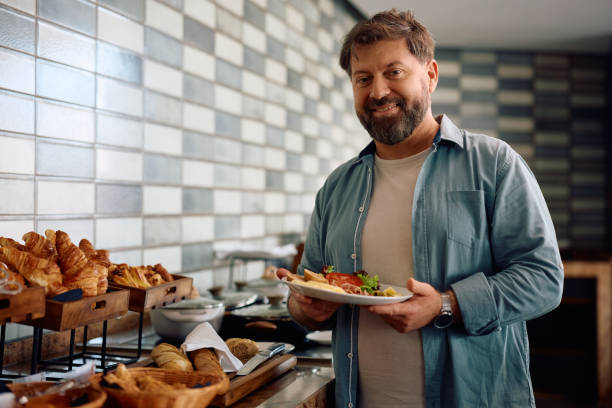 istock Happy man having breakfast while staying at the hotel and looking at camera. 2134925291