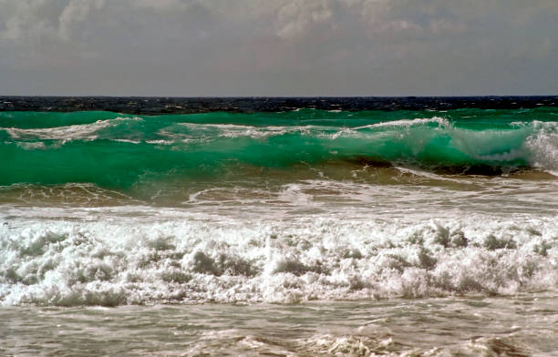 waves breaking on the sand of a beach against the sky