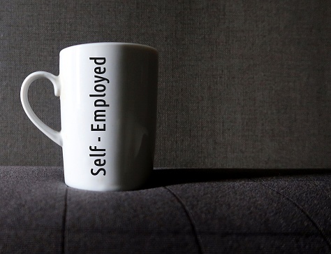 Coffee mug with inscription text Self-employed - means independent contractor or  sole proprietor who earn self-employment income - work for themselves in  variety of professions and occupations