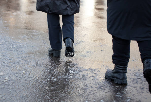 istock A man and a woman are walking through a puddle on a cold winter day 2134959812