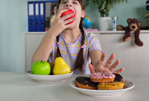 Diet or good health concept, teenage girl refuses junk food or junk food. Donuts or desserts, and chooses healthy foods, such as fresh fruits or vegetables.