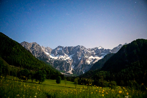 Zgornje Jezersko valley in Slovenia nighttime view with a starry night over the mountains  during a beautiful springtime night with the mountain range around the Grintovec mountain peak in the Kamnik–Savinja Alps.