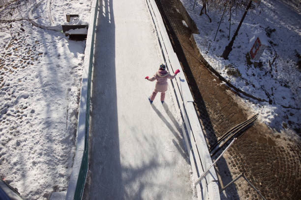 Beautiful girl is enjoying ice-skating on a winter sunny day. High angle view.