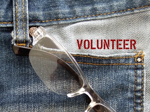 Jeans pocket with text VOLUNTEER, a person who does something or helping others willingly without being forced or paid to do