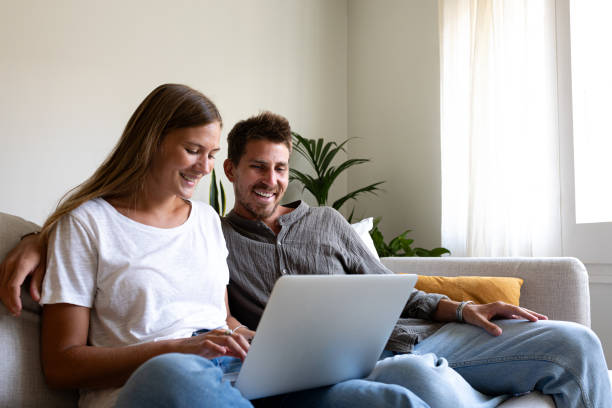 istock Happy young couple using laptop relaxing sitting on the sofa ordering online. Copy space. 2135021832