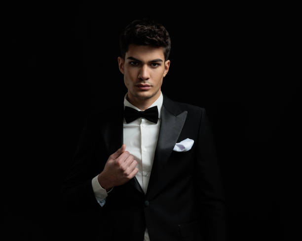 istock attractive man wearing black suit and bowtie fixing collar 2135025024