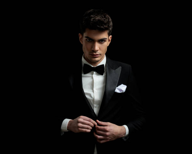 istock sexy young man unbuttoning his black tuxedo 2135027034