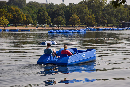 London, UK - September 6 2023: people on a blue pedal boat on The Serpentine lake in Hyde Park.