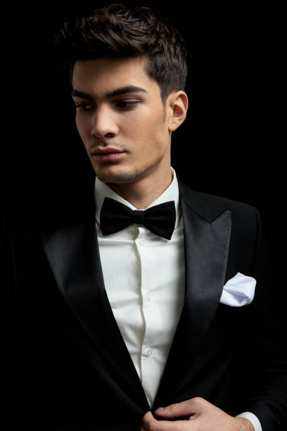 istock sexy young man buttoning black tux looking down to side 2135029800