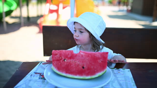 Cute little girl eating watermelon outdoors.
