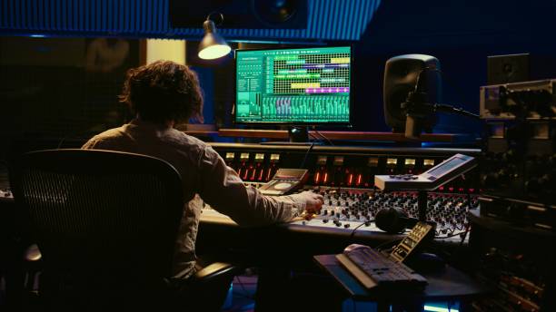 istock Music producer editing tracks with mixing console and audio software in studio 2135040378