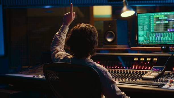 istock Sound engineer counting down for artist in vocal booth to start singing 2135044479