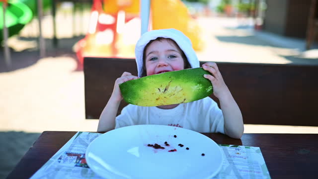 Cute toddler girl eating a slice of watermelon.