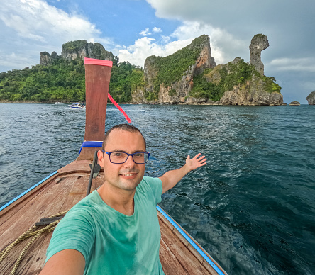 Young man taking selfies on the tour boat at the Chicken island in Thailand.