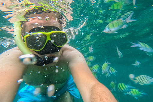 Young man taking selfies while snorkeling in the Andaman sea in Thailand.