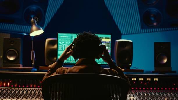 istock Sound designer editing tracks by adjusting volume levels with panel board knobs 2135055522