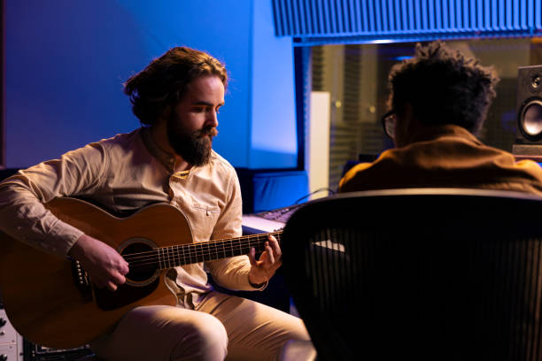 sänger spielt elektroakustische gitarre, um seine melodien aufzunehmen und einen hit zu komponieren - control room audio stock-fotos und bilder