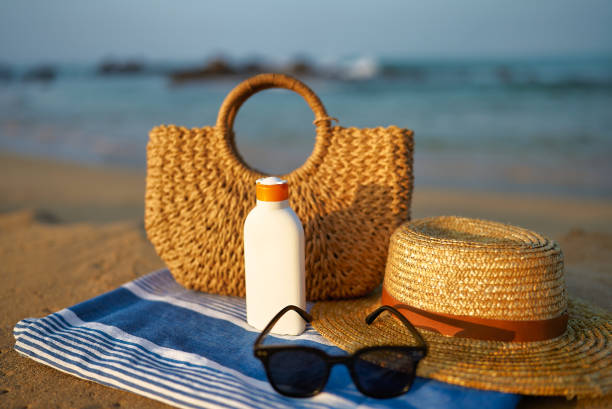 istock Straw hat rests next to sunscreen bottle on blue towel sunglasses, beach bag on sandy shore. Summer essentials for skin safety, leisure by sea, UV protection in coastal setting 2135074210