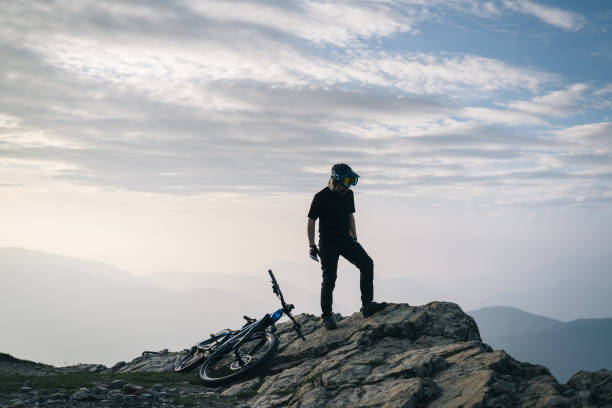Male mountain biker pauses on mountain top above valley