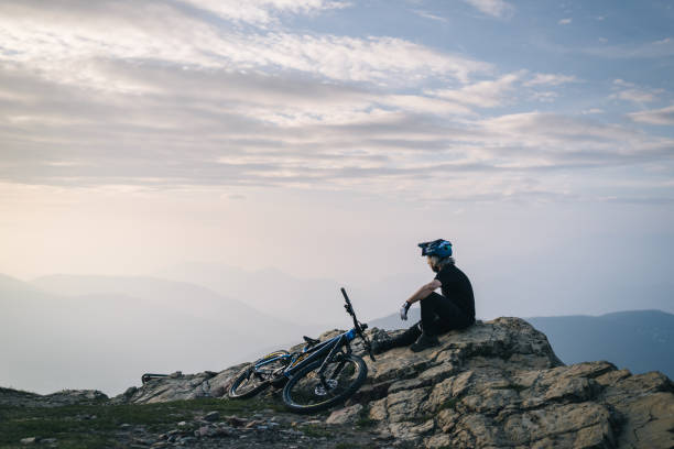 Male mountain biker pauses on mountain top above valley
