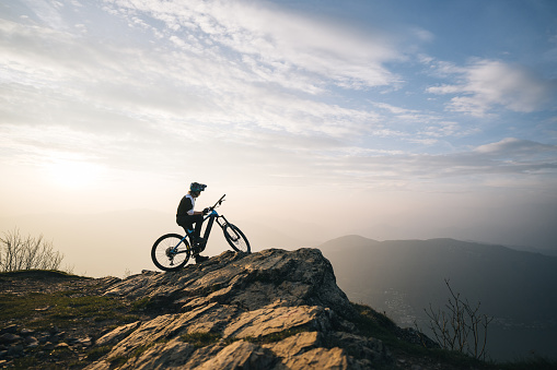 Male mountain biker pauses on mountain top above valley