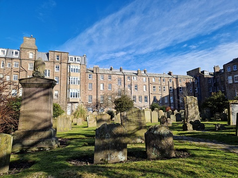 Gravestones in the Howff cemetery, Dundee, Scotland with tenement buildings in the background