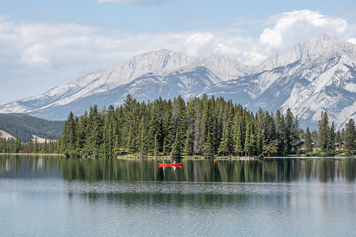 Jasper, Canada – May 26, 2023: A canoe floating on water with mountains and Jasper National Park in the background