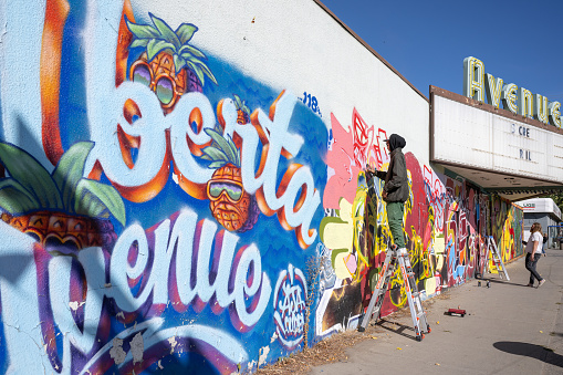 Edmonton, Canada – September 17, 2022: A graffiti artist standing on a ladder and painting a wall