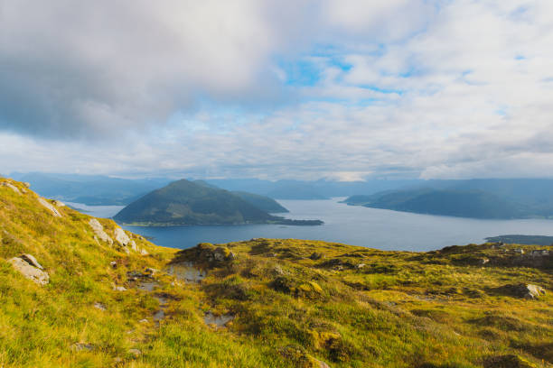 Dramatic view of meadow on the mountain peaks with background view of the fjord covered by the soft sunshine in Western Norway